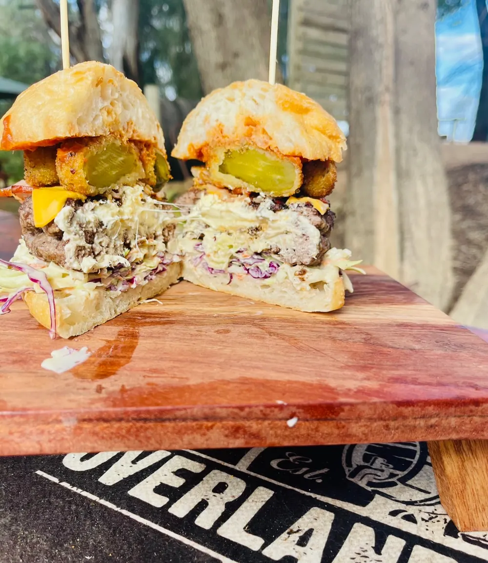 A towering burger on a timber board