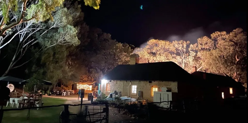 The hotel lit up at night under the gum trees