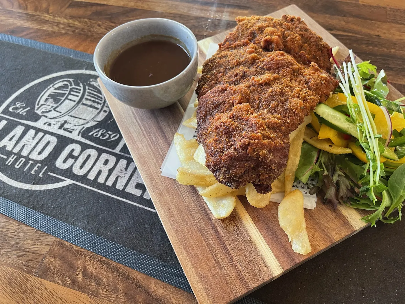Chicken schnitzel with chips and gravy on a timber board