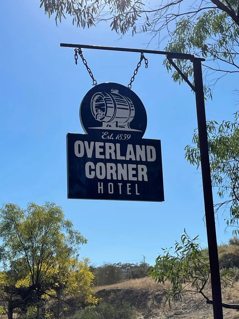 The hanging Overland Corner Hotel sign against a blue sky